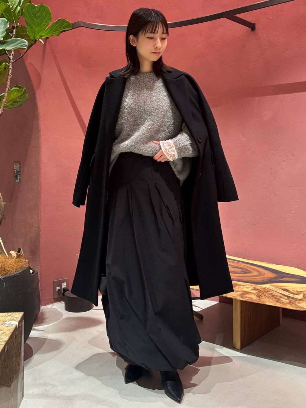 グレー系のニット/セーター、ホワイト系のTシャツ/カットソー、ブラック系のチェスターコートを着用したレディースの秋コーディネートの3枚目の写真