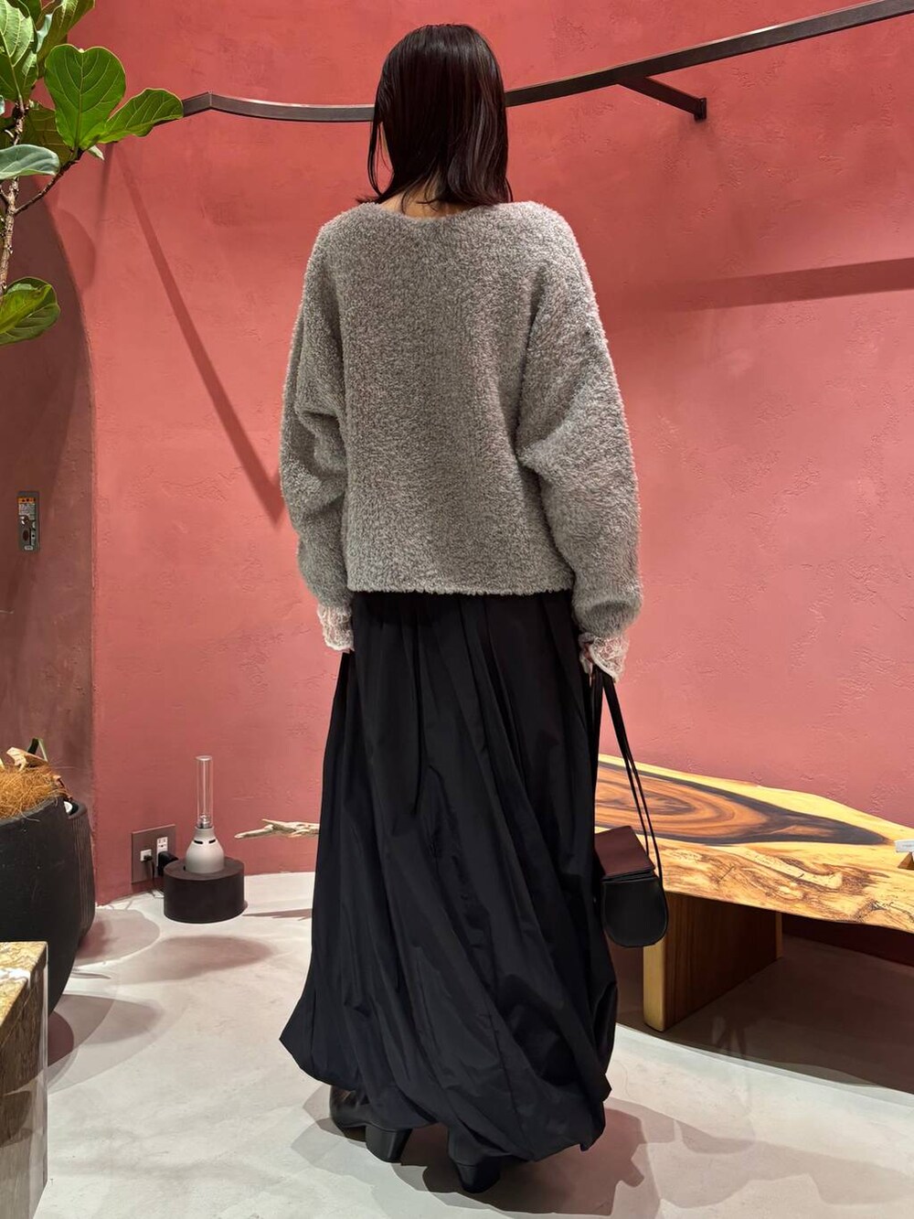 グレー系のニット/セーター、ホワイト系のTシャツ/カットソー、ブラック系のチェスターコートを着用したレディースの秋コーディネートの2枚目の写真