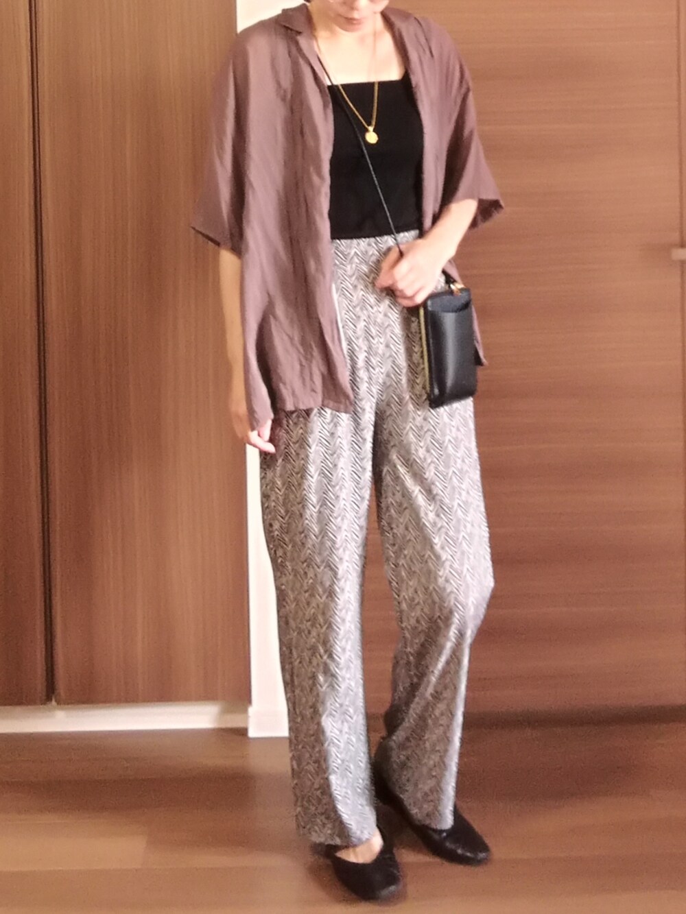 ブラック系のパンツ、ブラック系のショルダーバッグ、ブラウン系のシャツ/ブラウスを着用したレディースの秋コーディネートの2枚目の写真