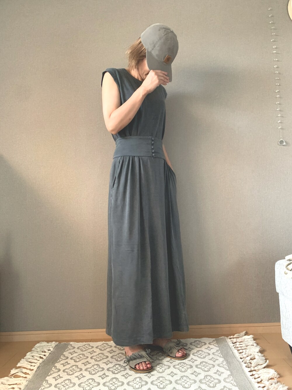 グレー系のサンダル、グレー系のワンピース、ブラウン系のキャップを着用したレディースの夏コーディネートの2枚目の写真