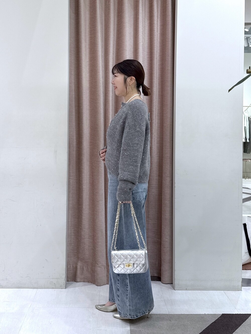 グレー系のカーディガン/ボレロ、グレー系のチューブトップ、ブルー系のデニムパンツを着用したレディースの秋コーディネートの3枚目の写真