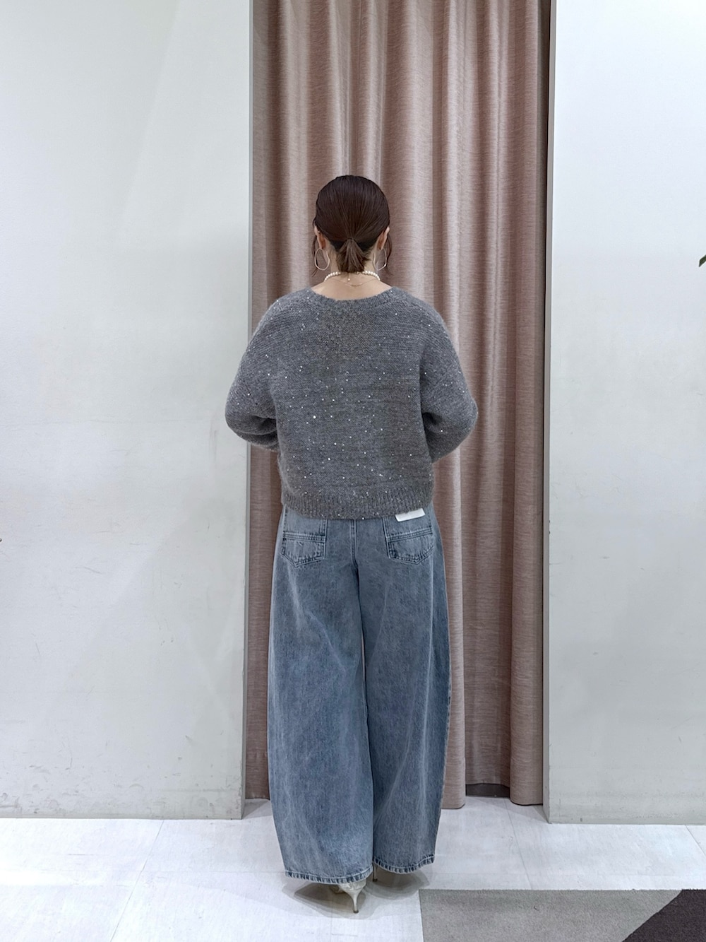 グレー系のカーディガン/ボレロ、グレー系のチューブトップ、ブルー系のデニムパンツを着用したレディースの秋コーディネートの4枚目の写真