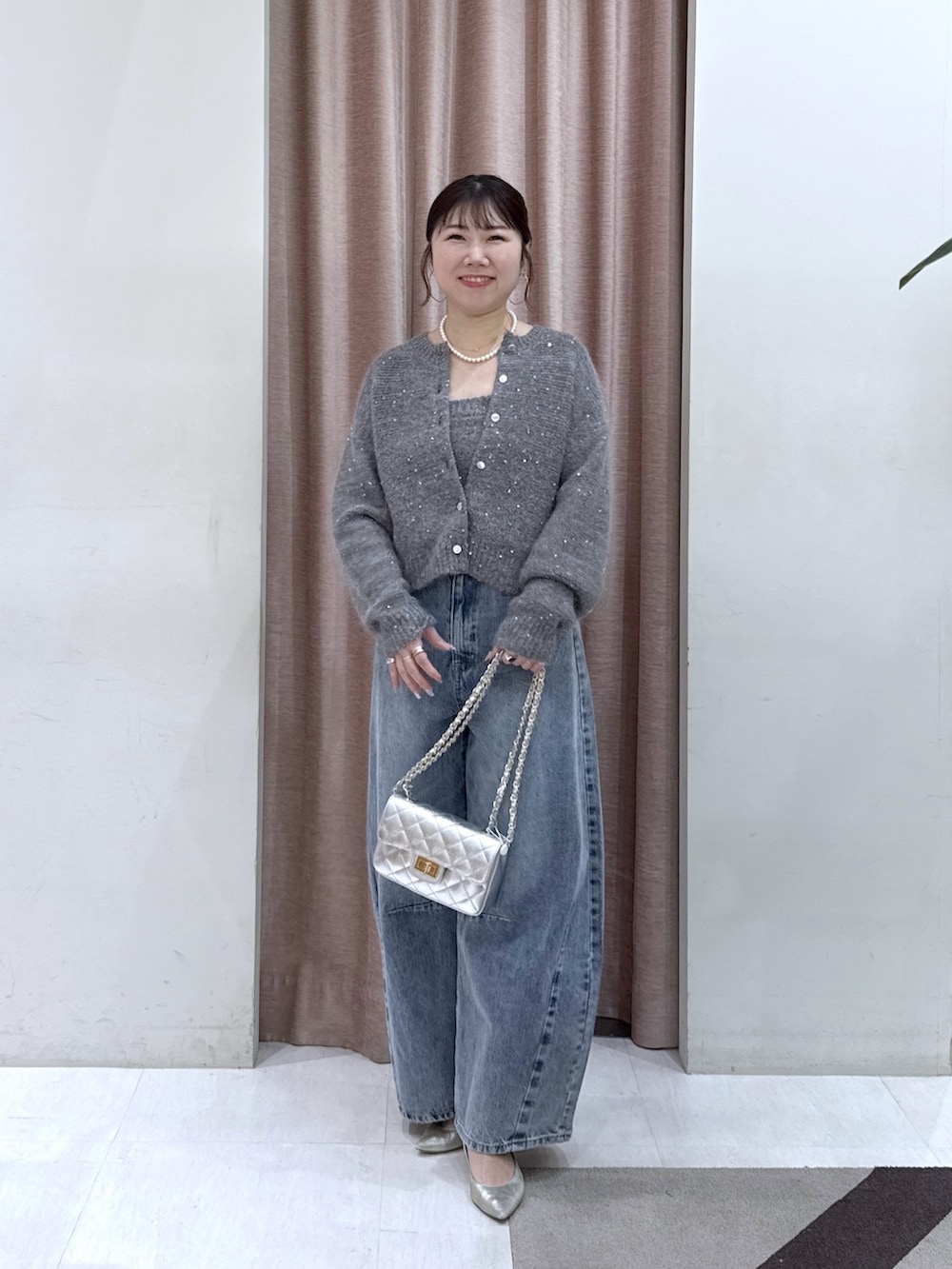 グレー系のカーディガン/ボレロ、グレー系のチューブトップ、ブルー系のデニムパンツを着用したレディースの秋コーディネートの2枚目の写真