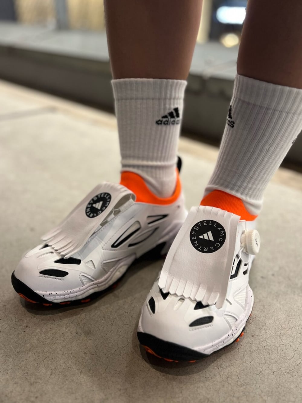 ピンク系のパンツ、イエロー系のナイロンジャケット、ホワイト系のスニーカーを着用したレディースの春コーディネートの4枚目の写真