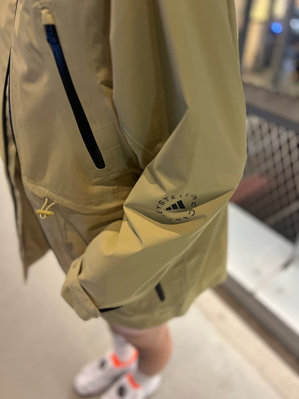 ピンク系のパンツ、イエロー系のナイロンジャケット、ホワイト系のスニーカーを着用したレディースの春コーディネートの2枚目の写真