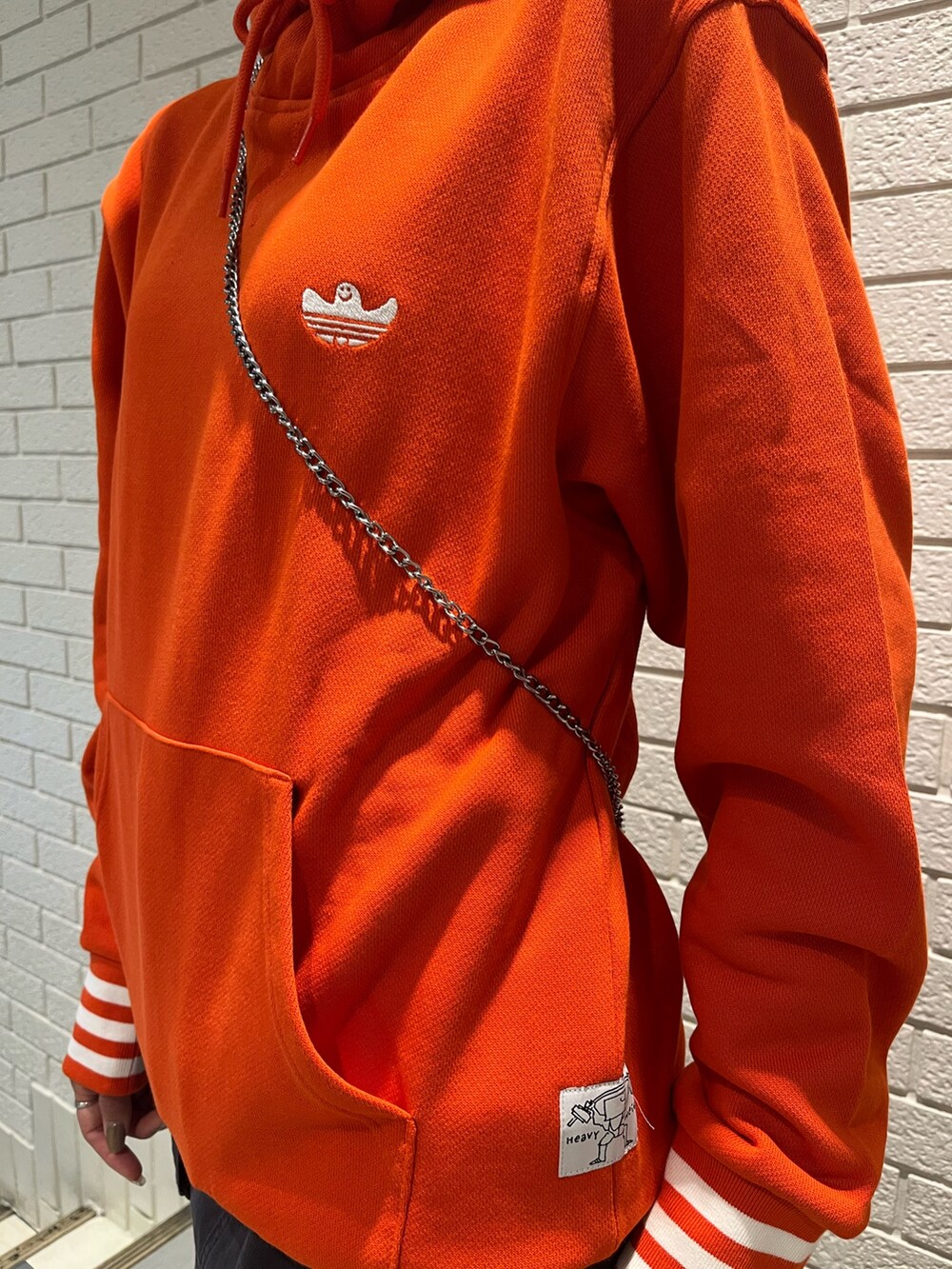 オレンジ系のパーカー、ブラック系のシューズを着用したレディースの秋コーディネートの3枚目の写真