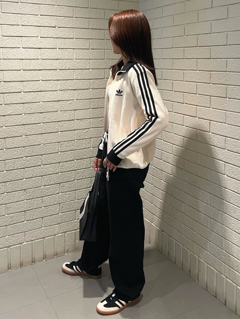 ホワイト系のTシャツ/カットソー、ブラック系のショルダーバッグ、ブラック系のスニーカーを着用したレディースの春コーディネートの2枚目の写真