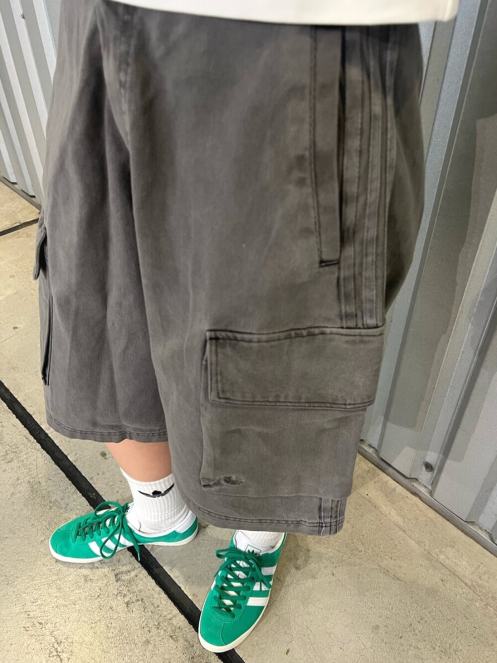 グリーン系のシューズ、ホワイト系のトップス、ブラック系のカーゴパンツを着用したレディースの夏コーディネートの3枚目の写真