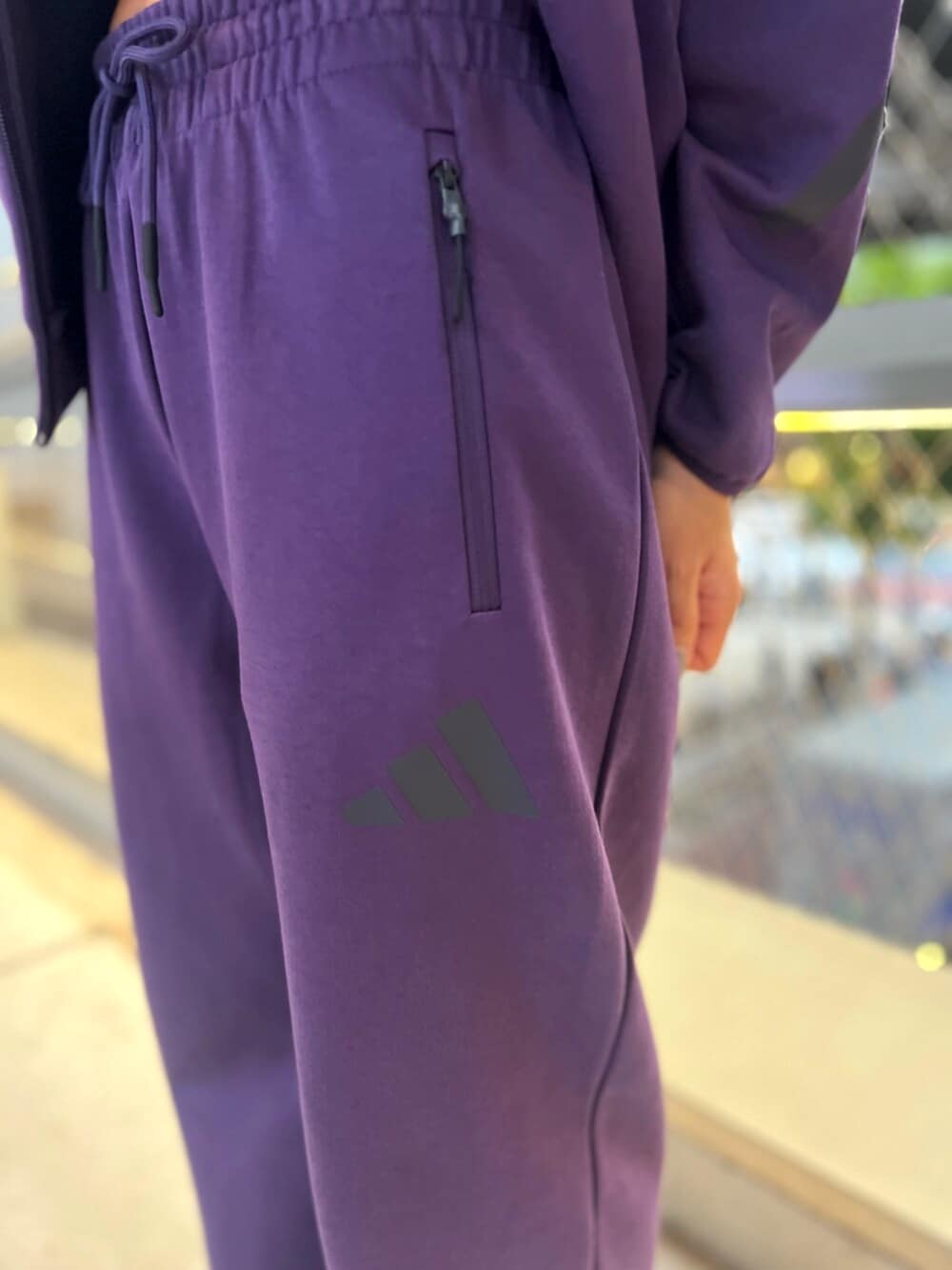 ブラック系のスニーカー、パープル系のパーカー、パープル系のパンツを着用したレディースの秋コーディネートの3枚目の写真