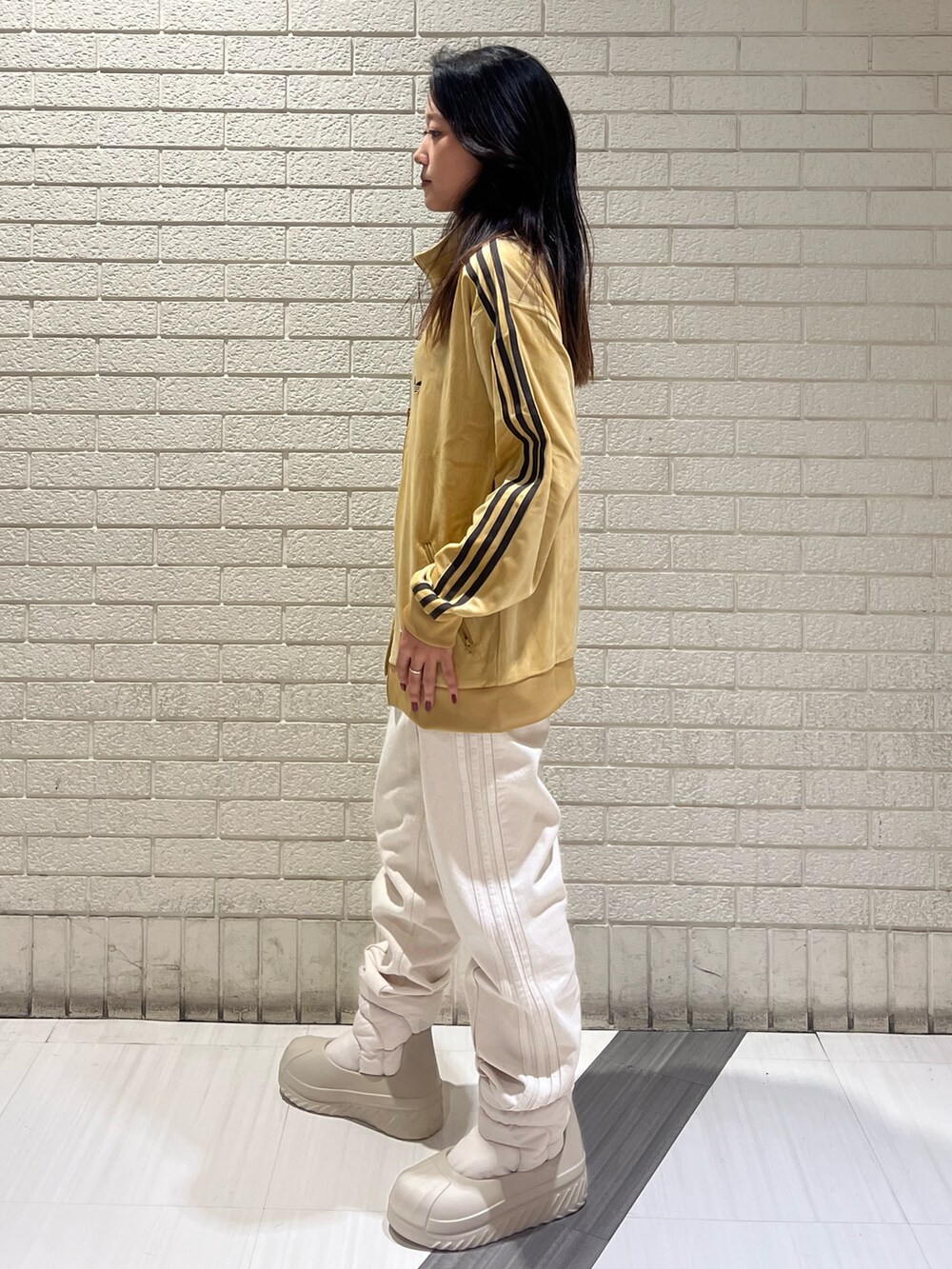 ベージュ系のジャージ、ホワイト系のデニムパンツ、ベージュ系のスニーカーを着用したレディースの秋コーディネートの2枚目の写真