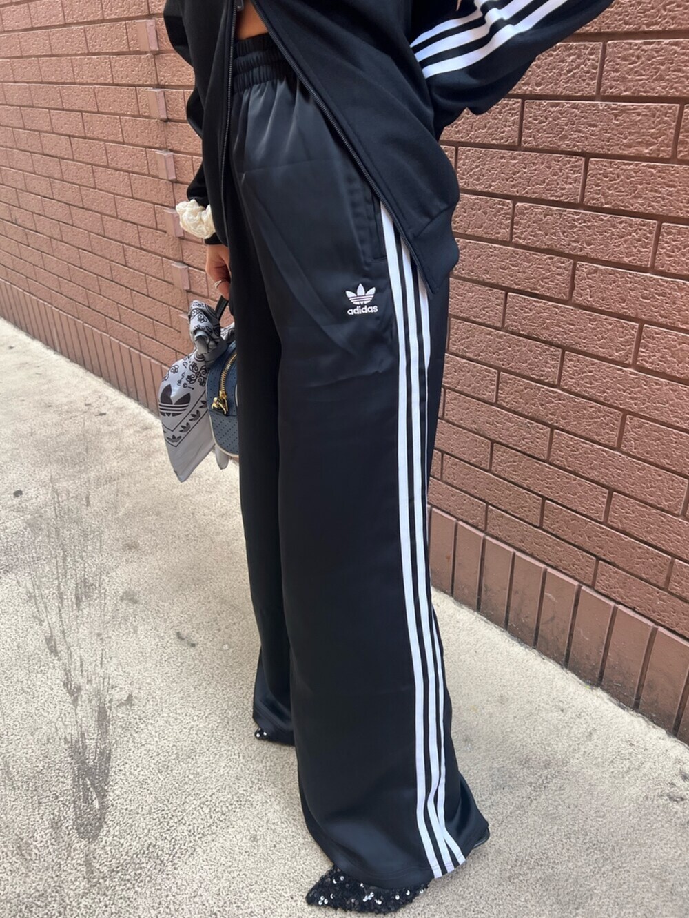 ブラック系のスウェットパンツ、ブラック系のジャージ、ブルー系のショルダーバッグを着用したレディースの冬コーディネートの4枚目の写真