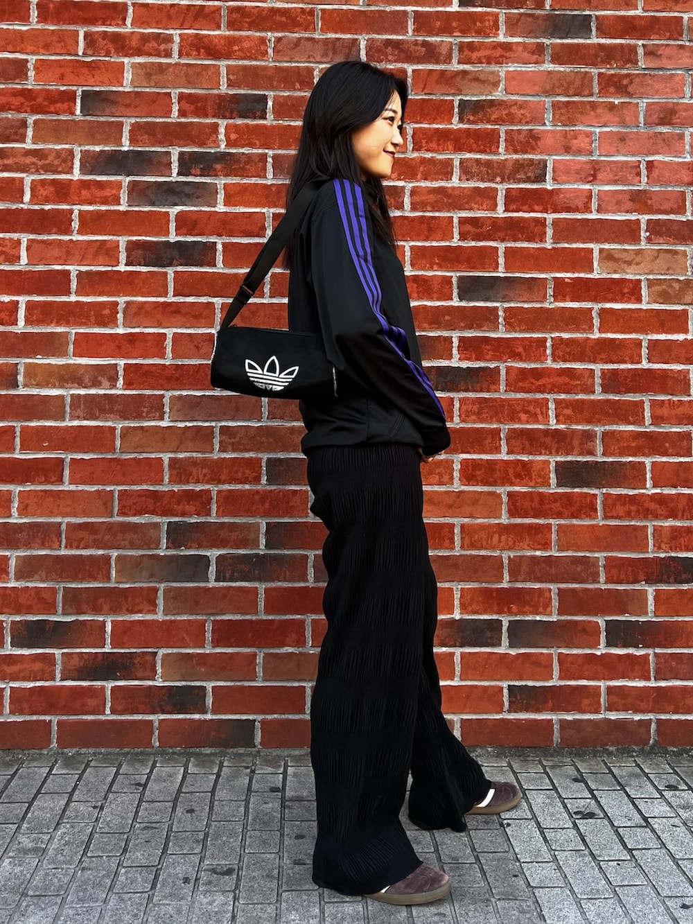 ブラック系のショルダーバッグ、ブラウン系のスニーカー、ブラック系のジャージを着用したレディースの春コーディネートの4枚目の写真