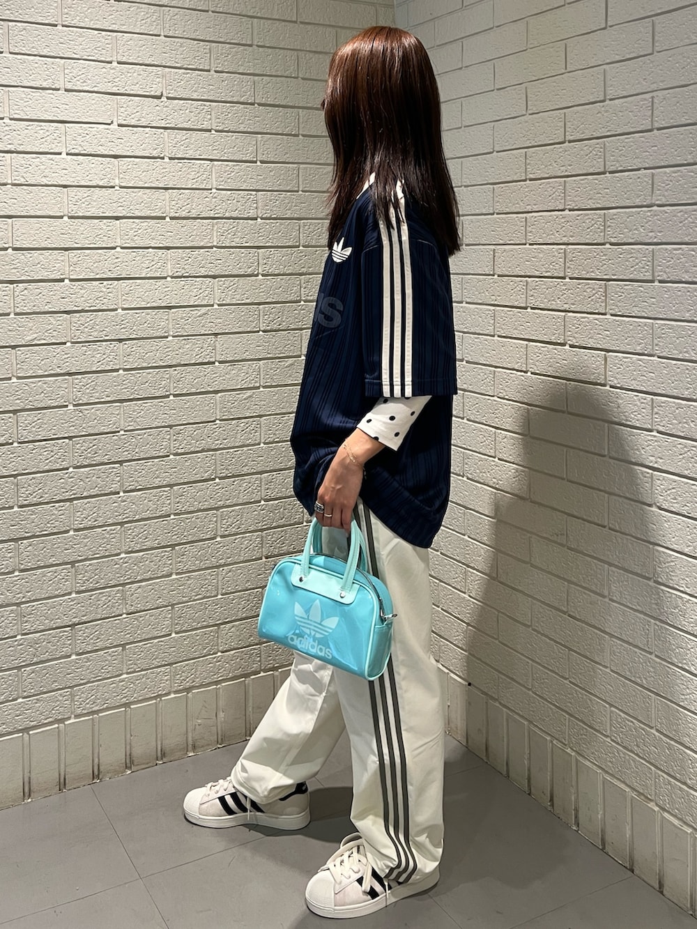 ブルー系のトップス、ホワイト系のその他パンツ、グリーン系のショルダーバッグを着用したレディースの春コーディネートの2枚目の写真
