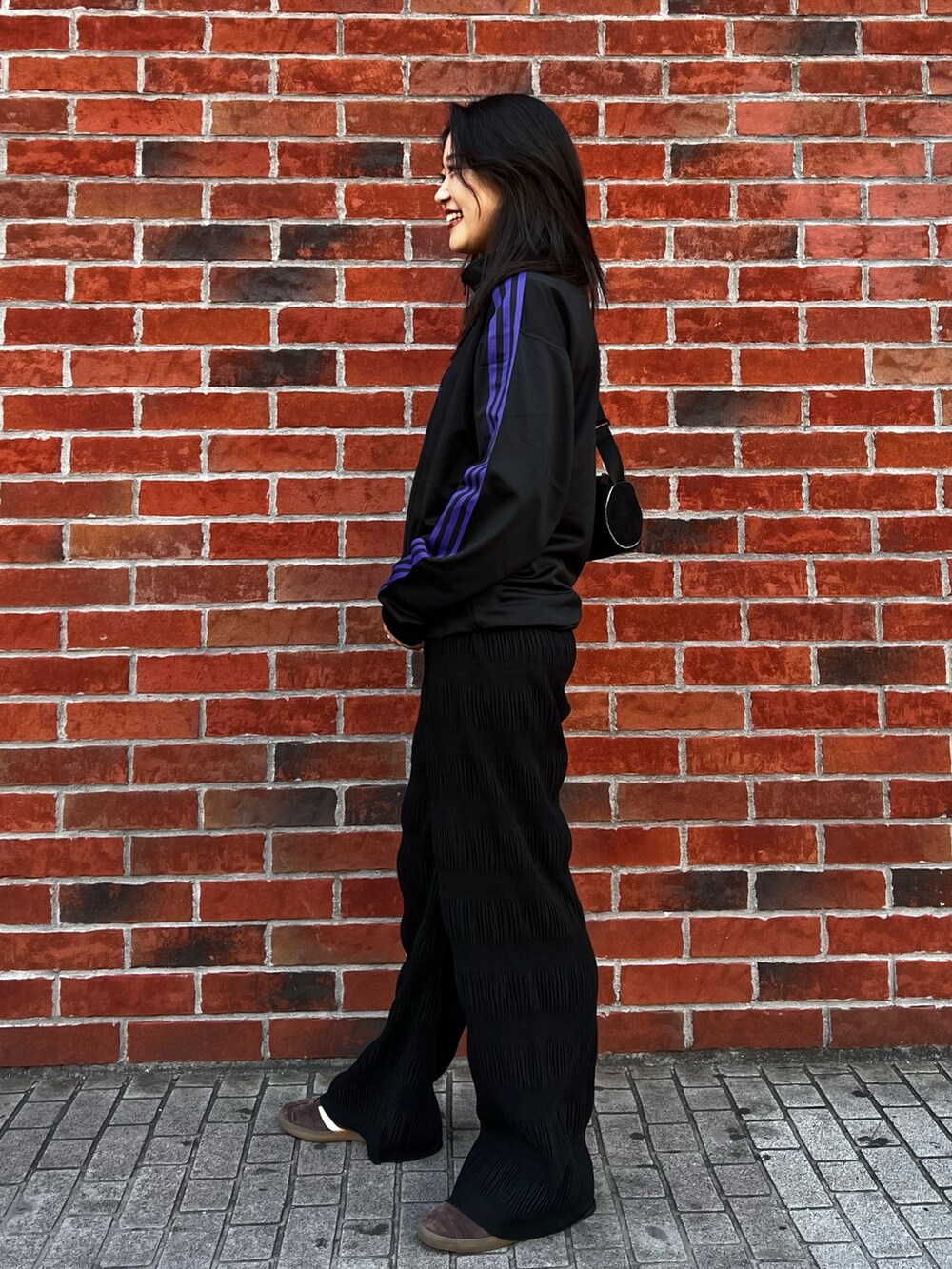 ブラック系のショルダーバッグ、ブラウン系のスニーカー、ブラック系のジャージを着用したレディースの春コーディネートの3枚目の写真