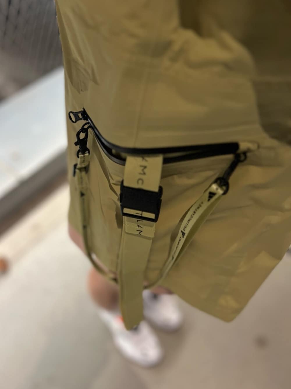 ピンク系のパンツ、イエロー系のナイロンジャケット、ホワイト系のスニーカーを着用したレディースの春コーディネートの3枚目の写真