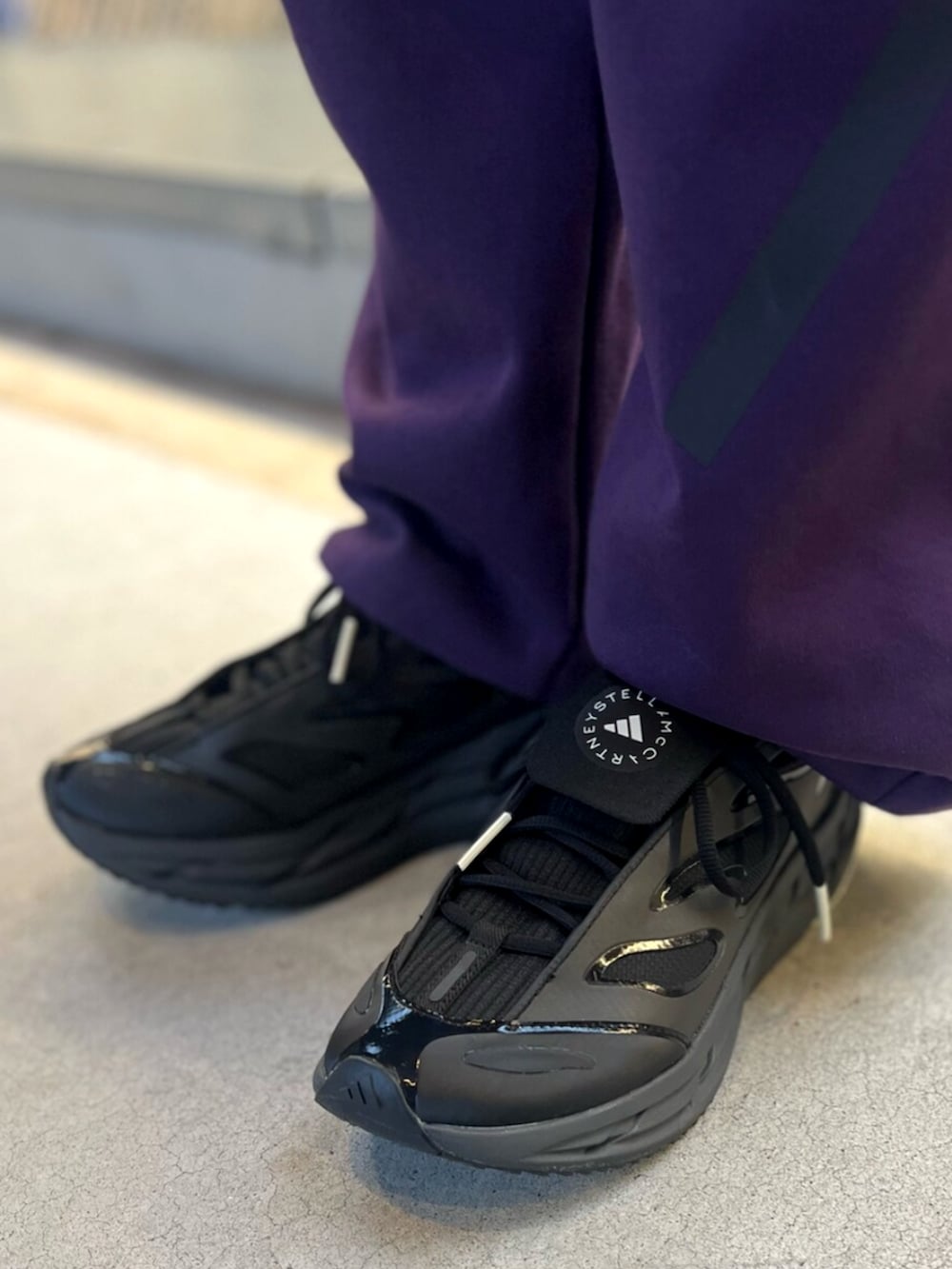 ブラック系のスニーカー、パープル系のパーカー、パープル系のパンツを着用したレディースの秋コーディネートの4枚目の写真