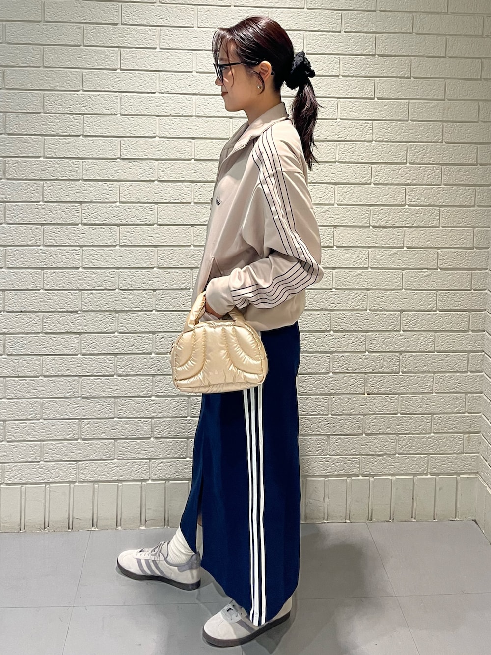 ベージュ系のジャージ、ブルー系のスカート、ベージュ系のスニーカーを着用したレディースの秋コーディネートの2枚目の写真