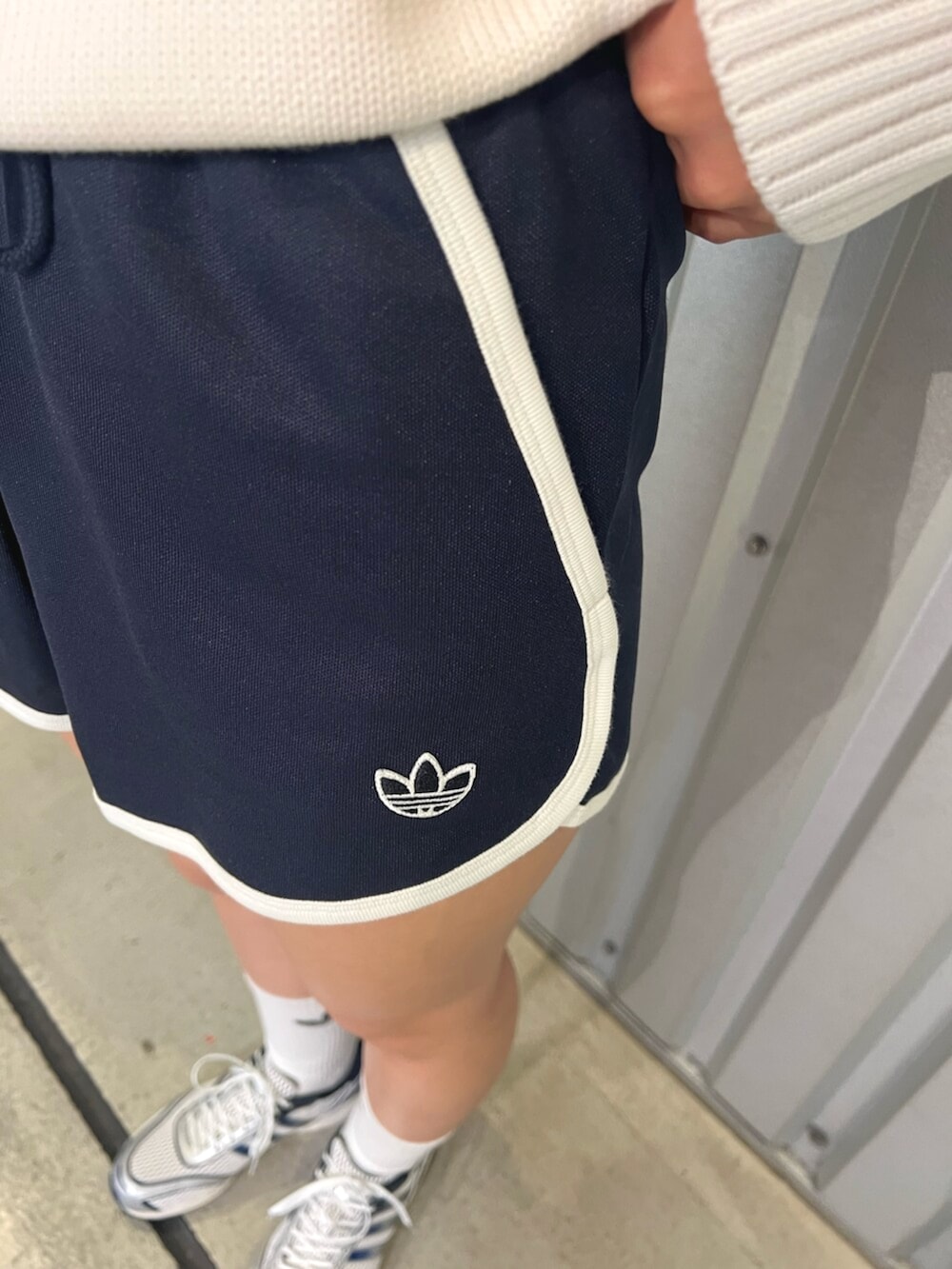 シルバー系のハンドバッグ、ホワイト系のシューズ、ブルー系のパンツを着用したレディースの夏コーディネートの3枚目の写真