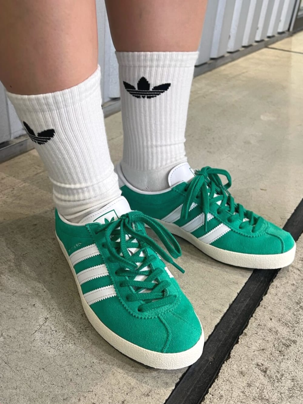 グリーン系のシューズ、ホワイト系のトップス、ブラック系のカーゴパンツを着用したレディースの夏コーディネートの4枚目の写真