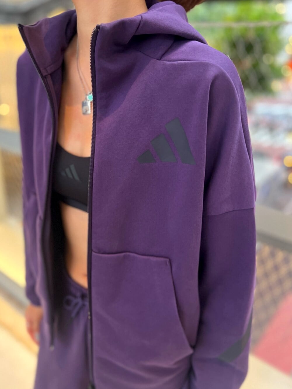 ブラック系のスニーカー、パープル系のパーカー、パープル系のパンツを着用したレディースの秋コーディネートの2枚目の写真