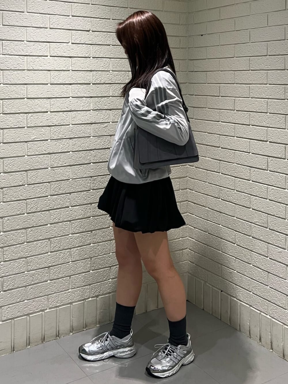 グレー系のトップス、グレー系のショルダーバッグを着用したレディースの春コーディネートの2枚目の写真