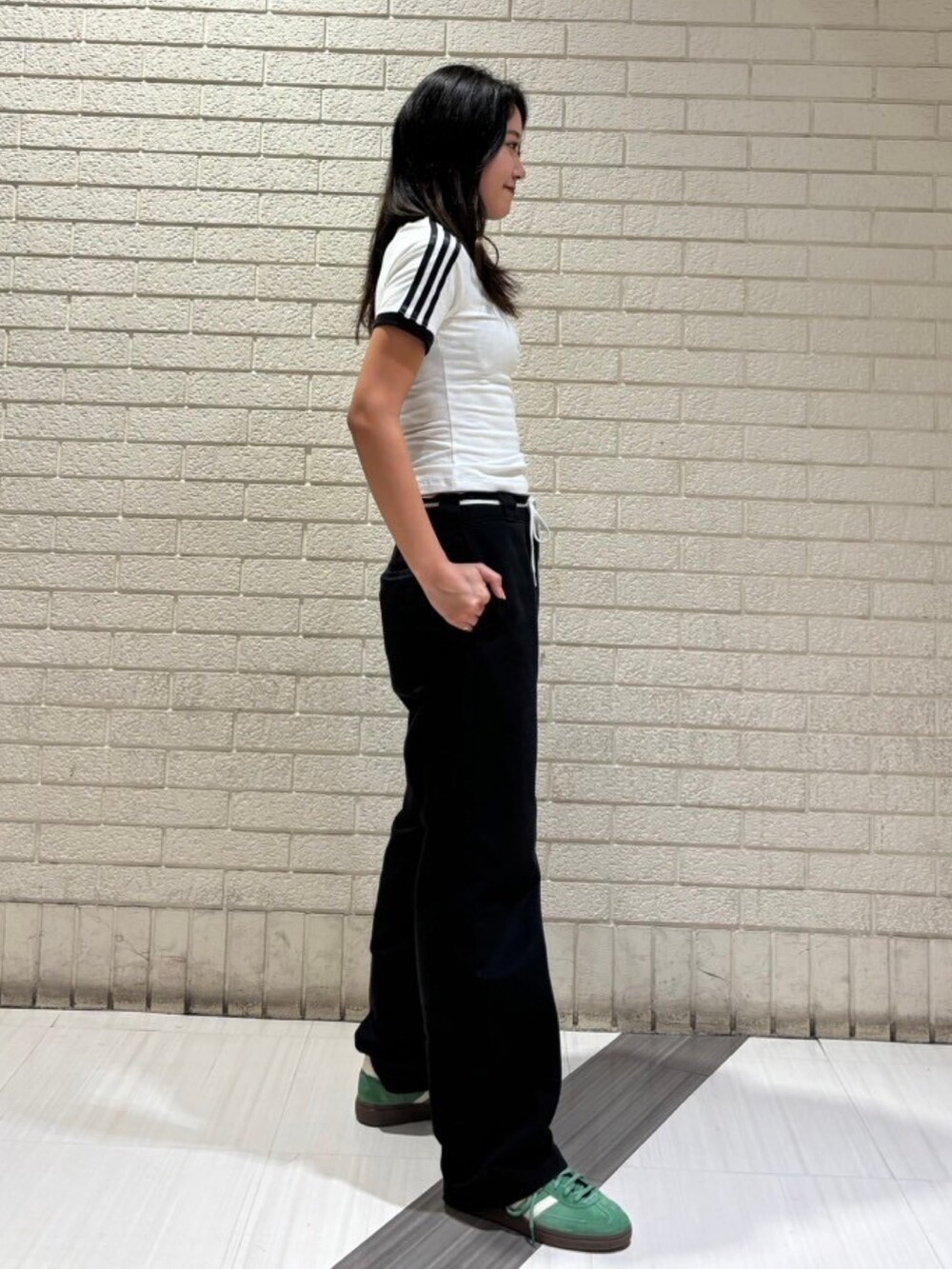 ホワイト系のトップス、グリーン系のスニーカーを着用したレディースの春コーディネートの3枚目の写真