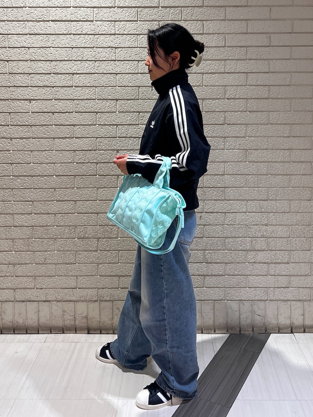 ブラック系のナイロンジャケット、グリーン系のハンドバッグ、ブラック系のスニーカーを着用したレディースの春コーディネートの2枚目の写真