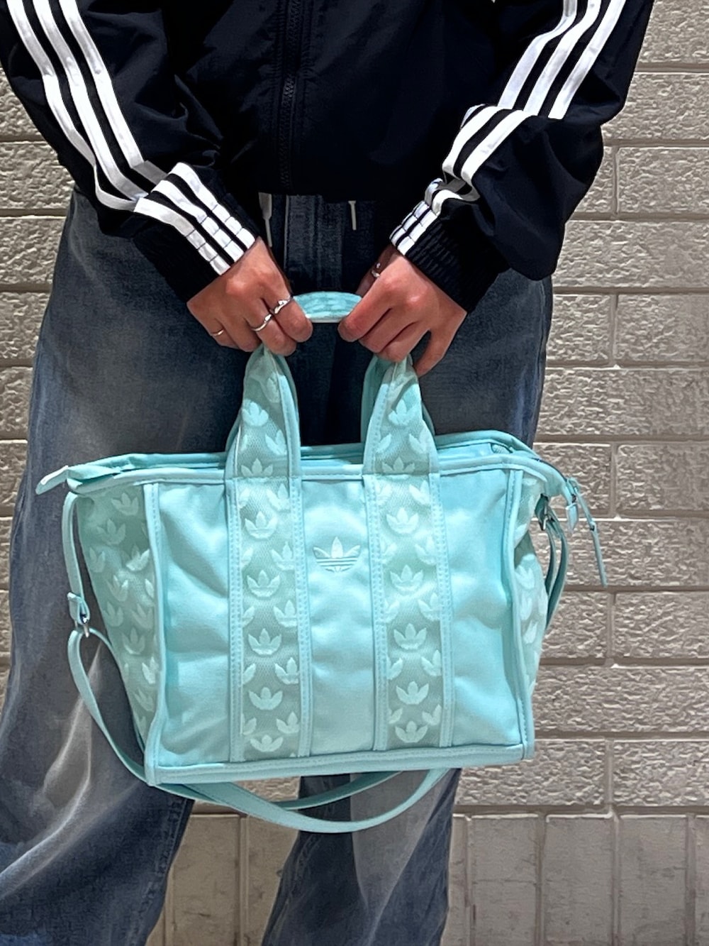 ブラック系のナイロンジャケット、グリーン系のハンドバッグ、ブラック系のスニーカーを着用したレディースの春コーディネートの4枚目の写真