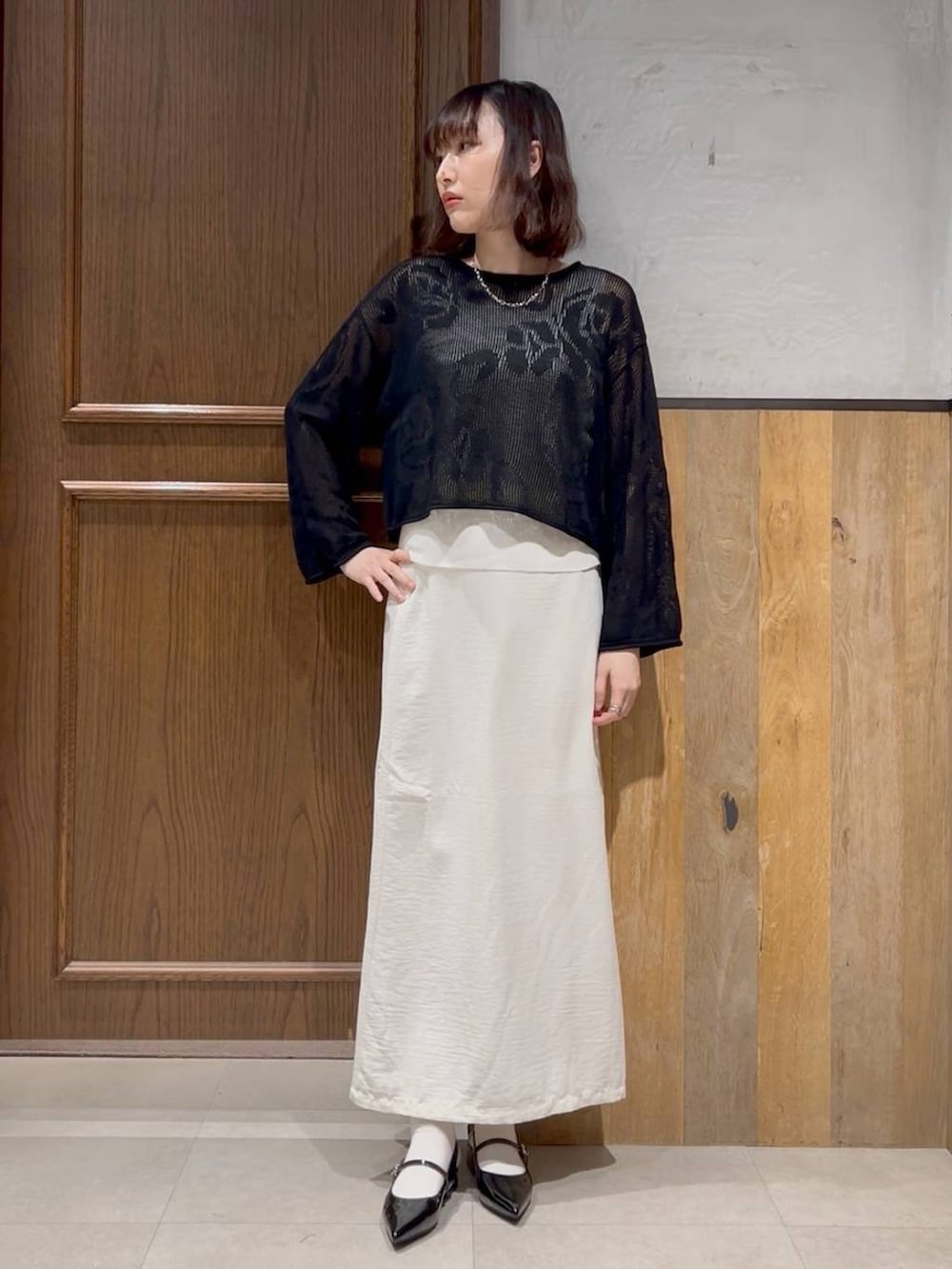 ブラック系のパンプス、ホワイト系のスカート、ホワイト系のタンクトップを着用したレディースの春コーディネートの2枚目の写真