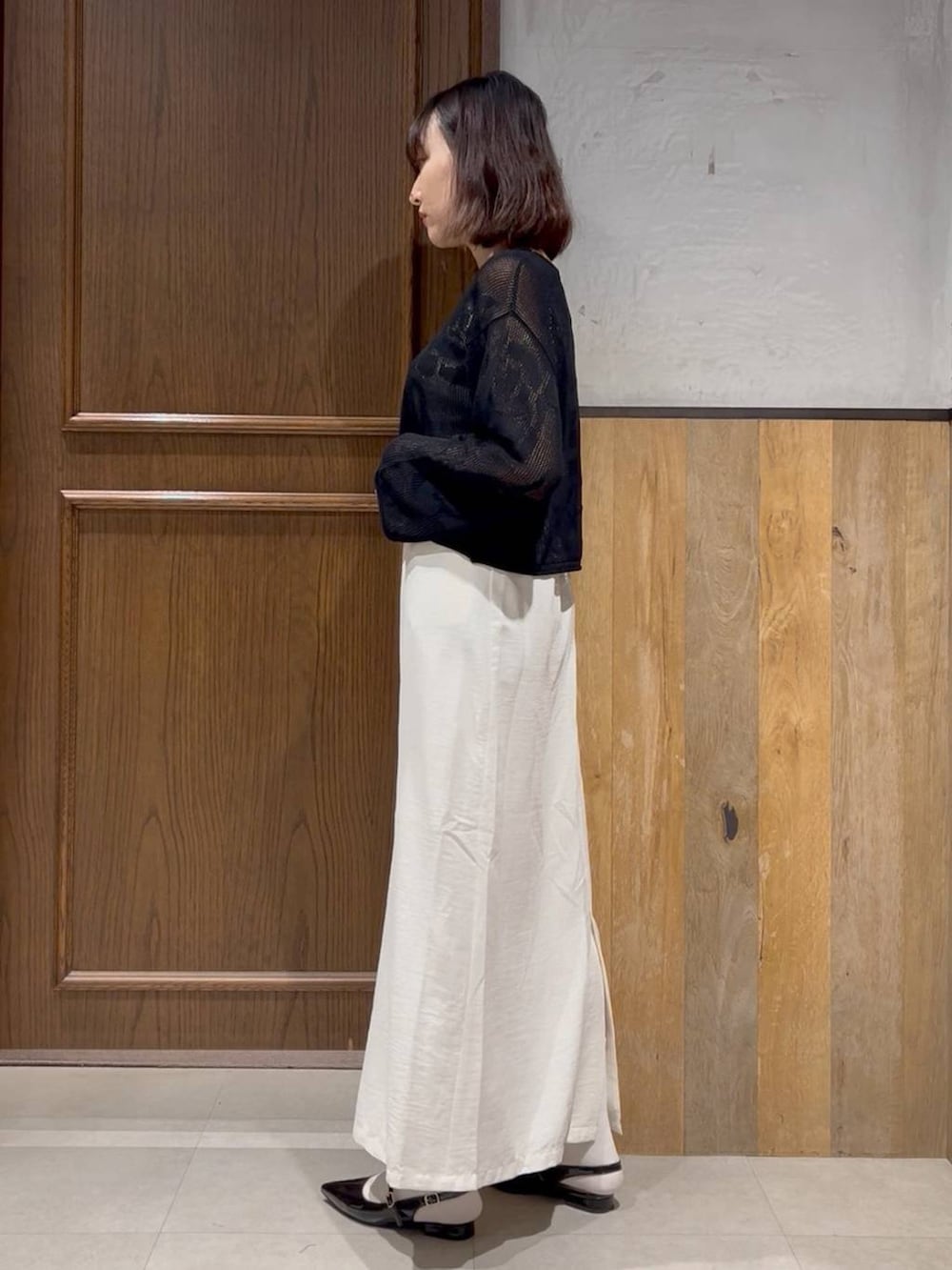 ブラック系のパンプス、ホワイト系のスカート、ホワイト系のタンクトップを着用したレディースの春コーディネートの3枚目の写真