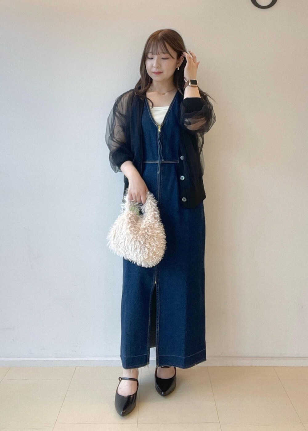 ホワイト系のタンクトップ、ベージュ系のハンドバッグ、ブラック系のパンプスを着用したレディースの秋コーディネートの2枚目の写真