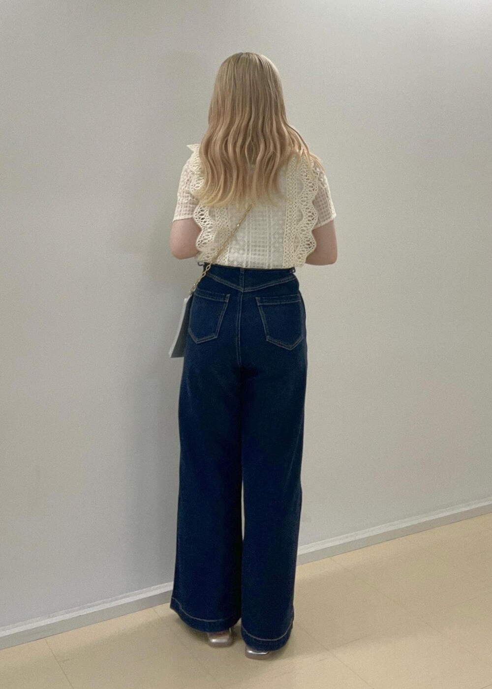 ブルー系のデニムパンツ、シルバー系のサンダル、シルバー系のショルダーバッグを着用したレディースの夏コーディネートの2枚目の写真
