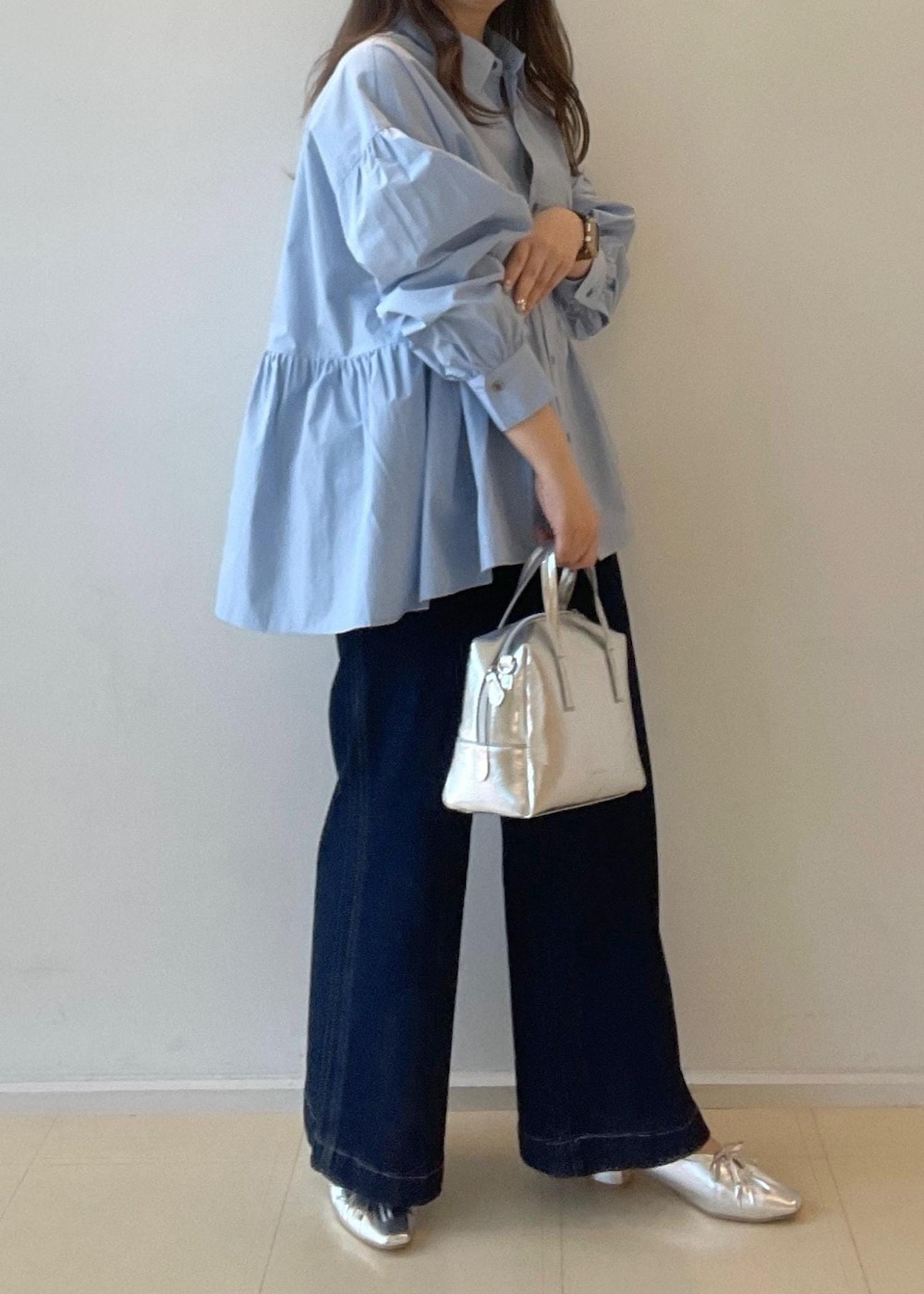 シルバー系のパンプス、ブルー系のデニムパンツ、シルバー系のボストンバッグを着用したレディースの秋コーディネートの5枚目の写真
