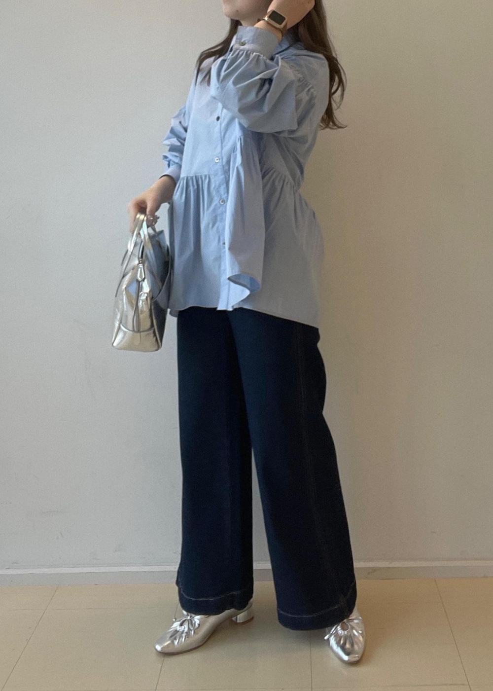 シルバー系のパンプス、ブルー系のデニムパンツ、シルバー系のボストンバッグを着用したレディースの秋コーディネートの6枚目の写真