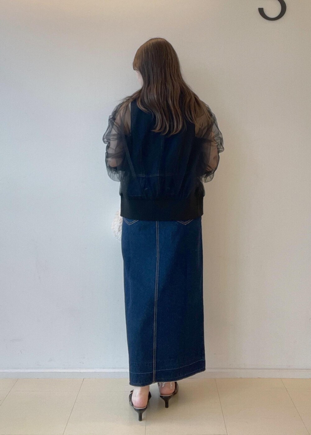 ホワイト系のタンクトップ、ベージュ系のハンドバッグ、ブラック系のパンプスを着用したレディースの秋コーディネートの3枚目の写真