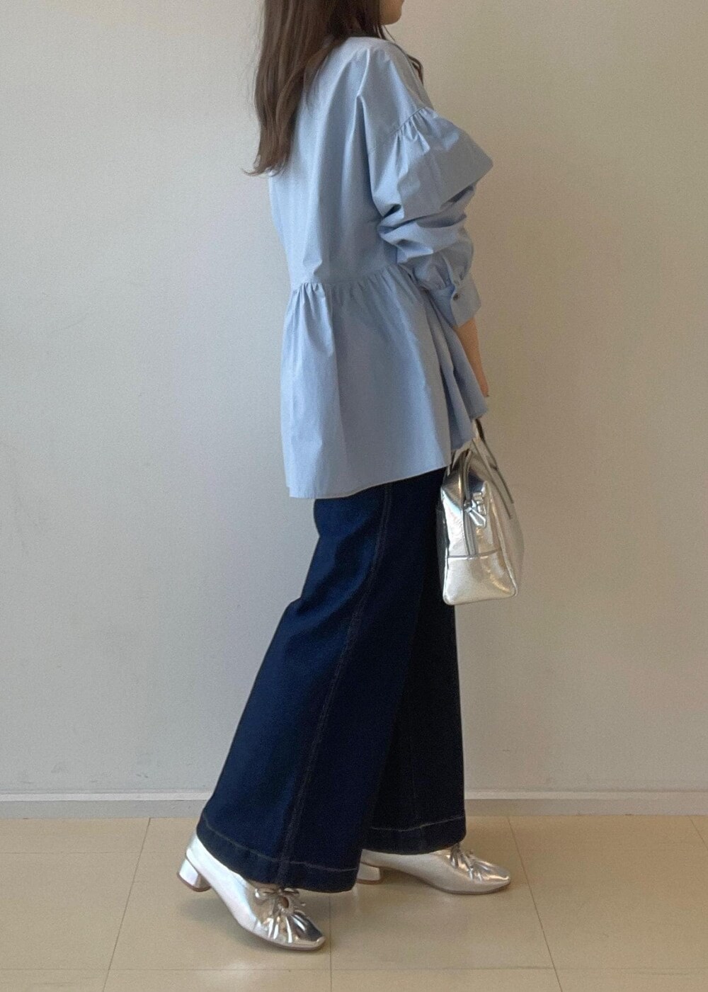 シルバー系のパンプス、ブルー系のデニムパンツ、シルバー系のボストンバッグを着用したレディースの秋コーディネートの4枚目の写真