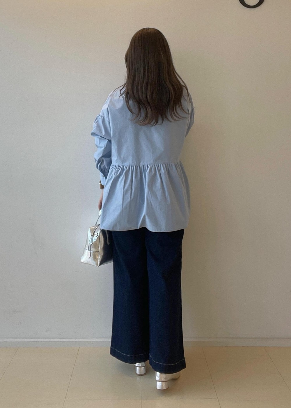 シルバー系のパンプス、ブルー系のデニムパンツ、シルバー系のボストンバッグを着用したレディースの秋コーディネートの2枚目の写真