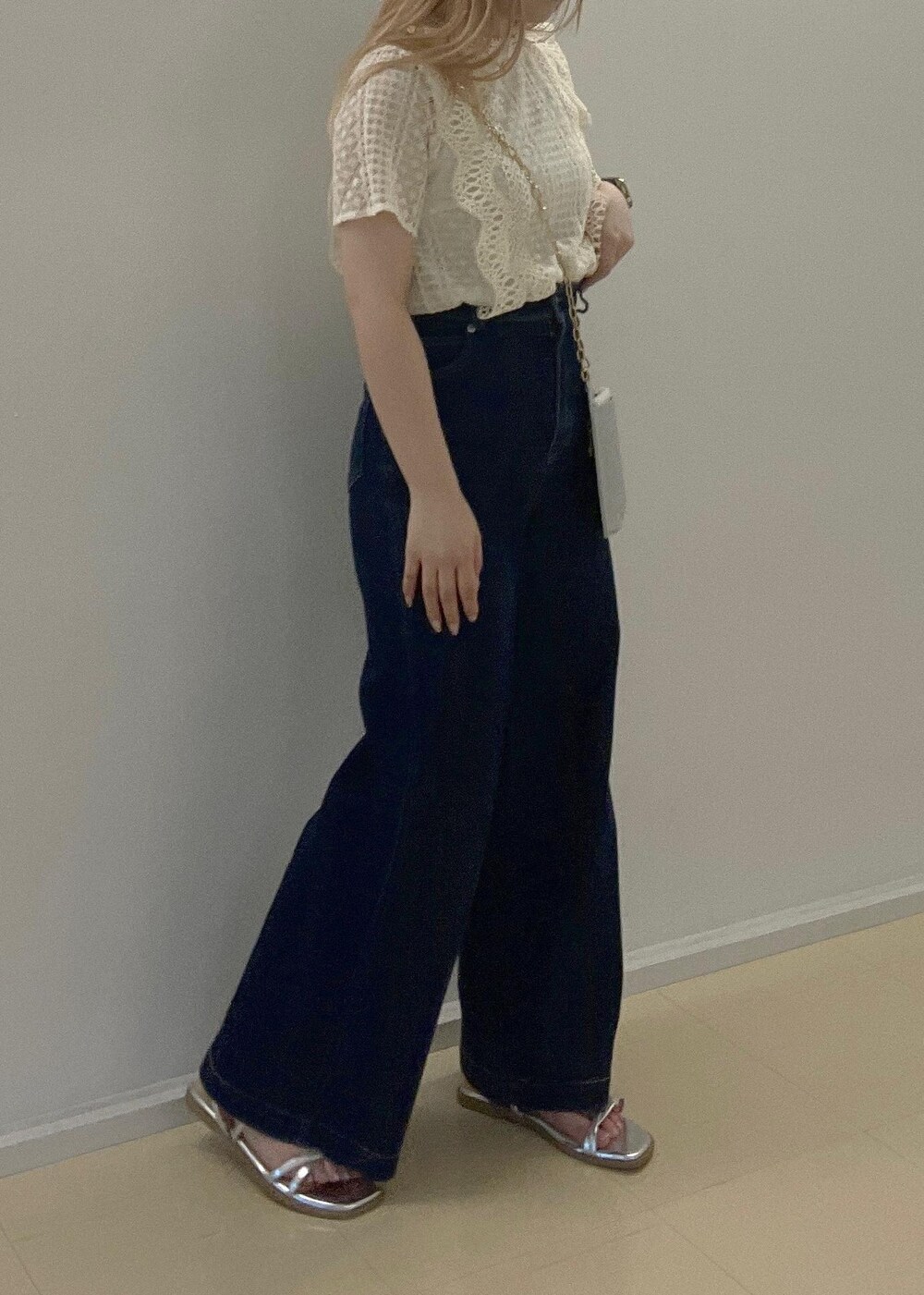 ブルー系のデニムパンツ、シルバー系のサンダル、シルバー系のショルダーバッグを着用したレディースの夏コーディネートの4枚目の写真