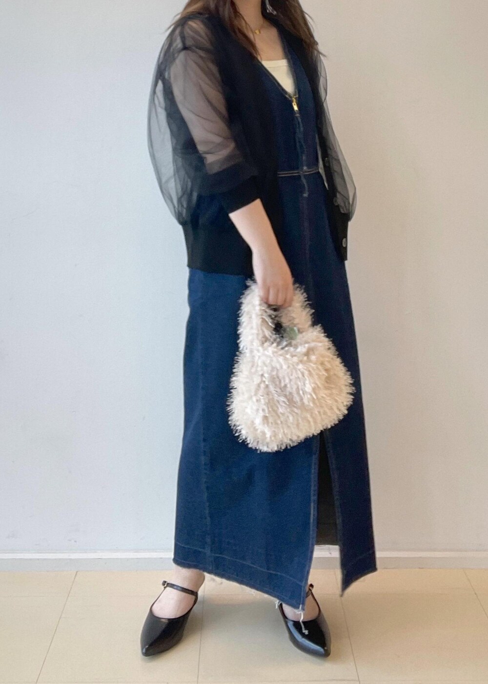 ホワイト系のタンクトップ、ベージュ系のハンドバッグ、ブラック系のパンプスを着用したレディースの秋コーディネートの4枚目の写真