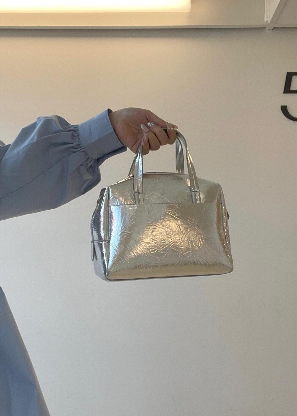 シルバー系のパンプス、ブルー系のデニムパンツ、シルバー系のボストンバッグを着用したレディースの秋コーディネートの10枚目の写真