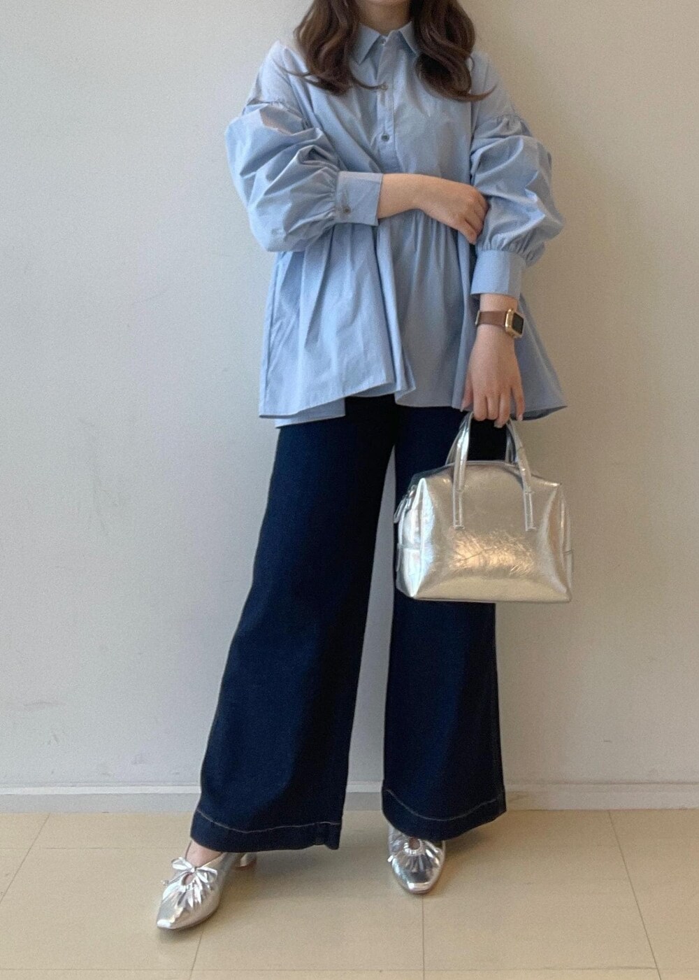 シルバー系のパンプス、ブルー系のデニムパンツ、シルバー系のボストンバッグを着用したレディースの秋コーディネートの3枚目の写真
