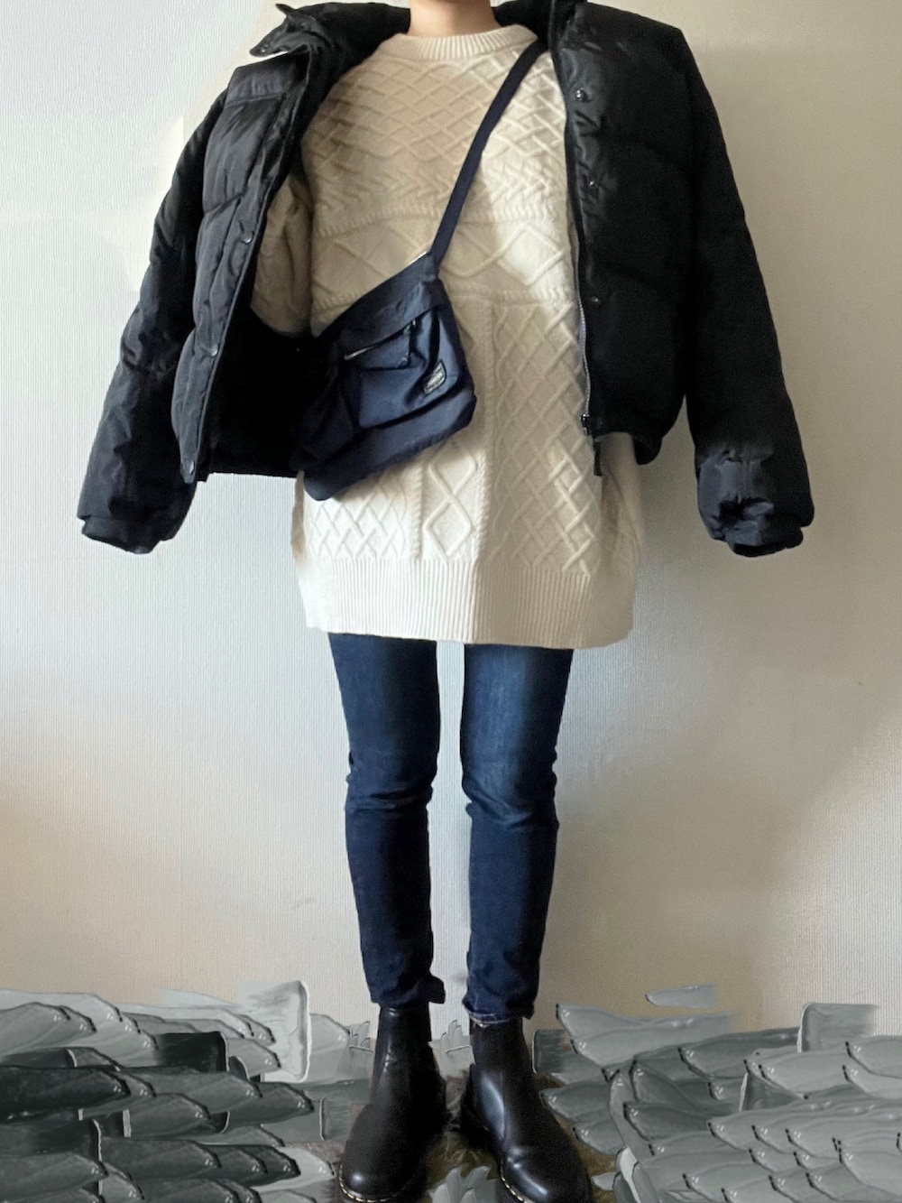 ブルー系のデニムパンツ、ホワイト系のニット/セーター、ブルー系のショルダーバッグを着用したレディースの冬コーディネートの2枚目の写真