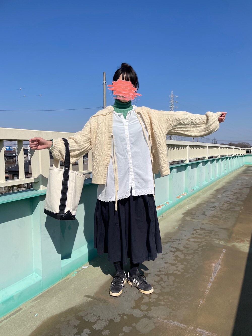 ブラック系のスニーカー、ブルー系のスカート、ホワイト系のトートバッグを着用したレディースの冬コーディネートの2枚目の写真