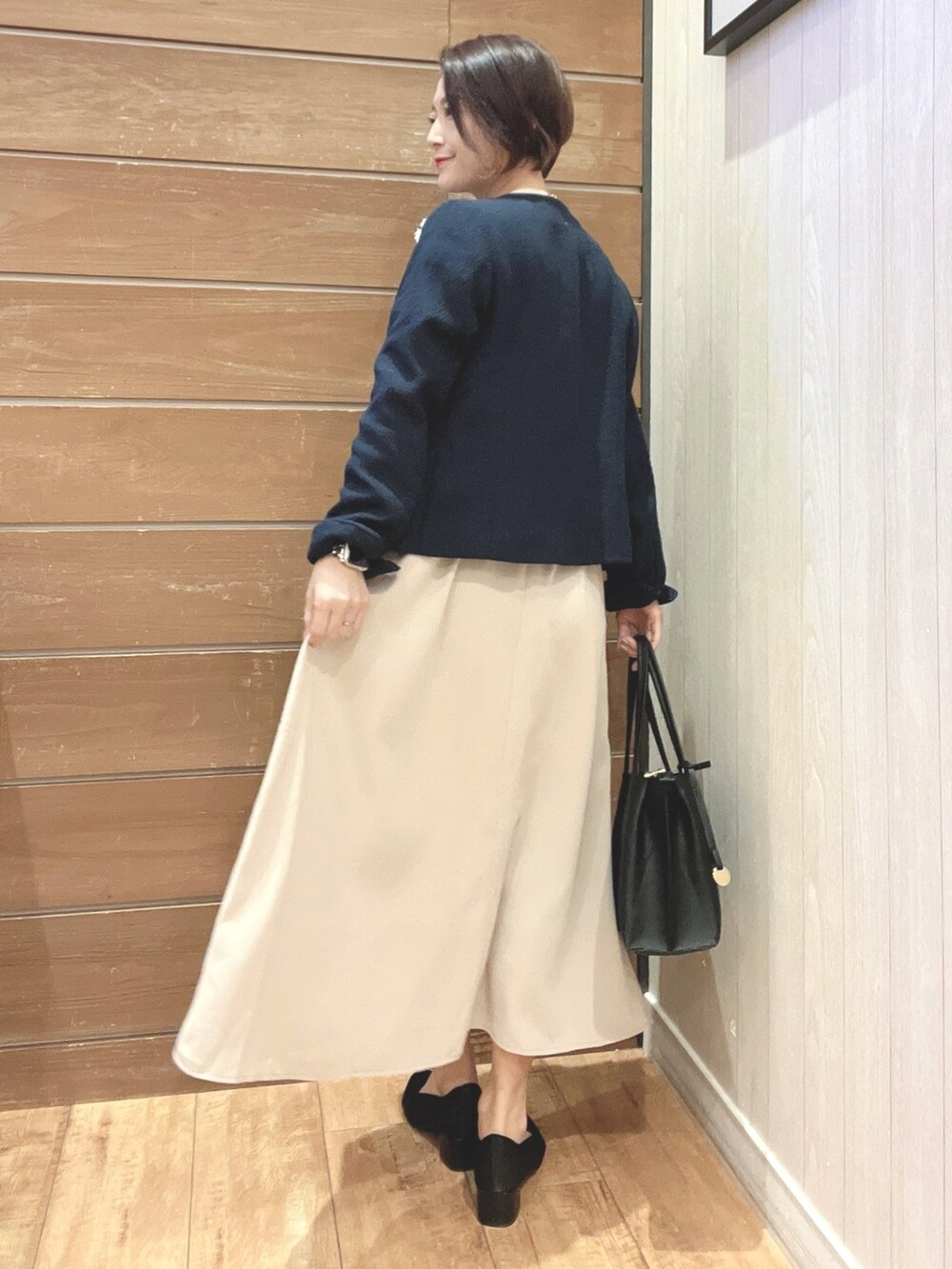 ブラック系のハンドバッグ、ブルー系のノーカラージャケット、ベージュ系のワンピースを着用したレディースの冬コーディネートの3枚目の写真