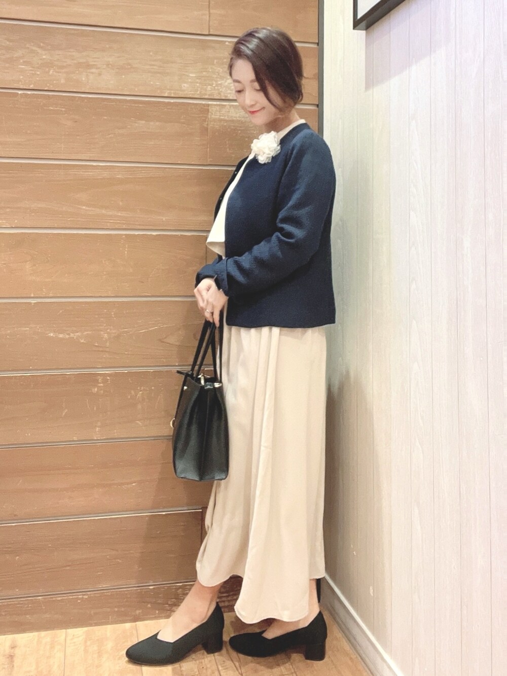 ブラック系のハンドバッグ、ブルー系のノーカラージャケット、ベージュ系のワンピースを着用したレディースの冬コーディネートの2枚目の写真