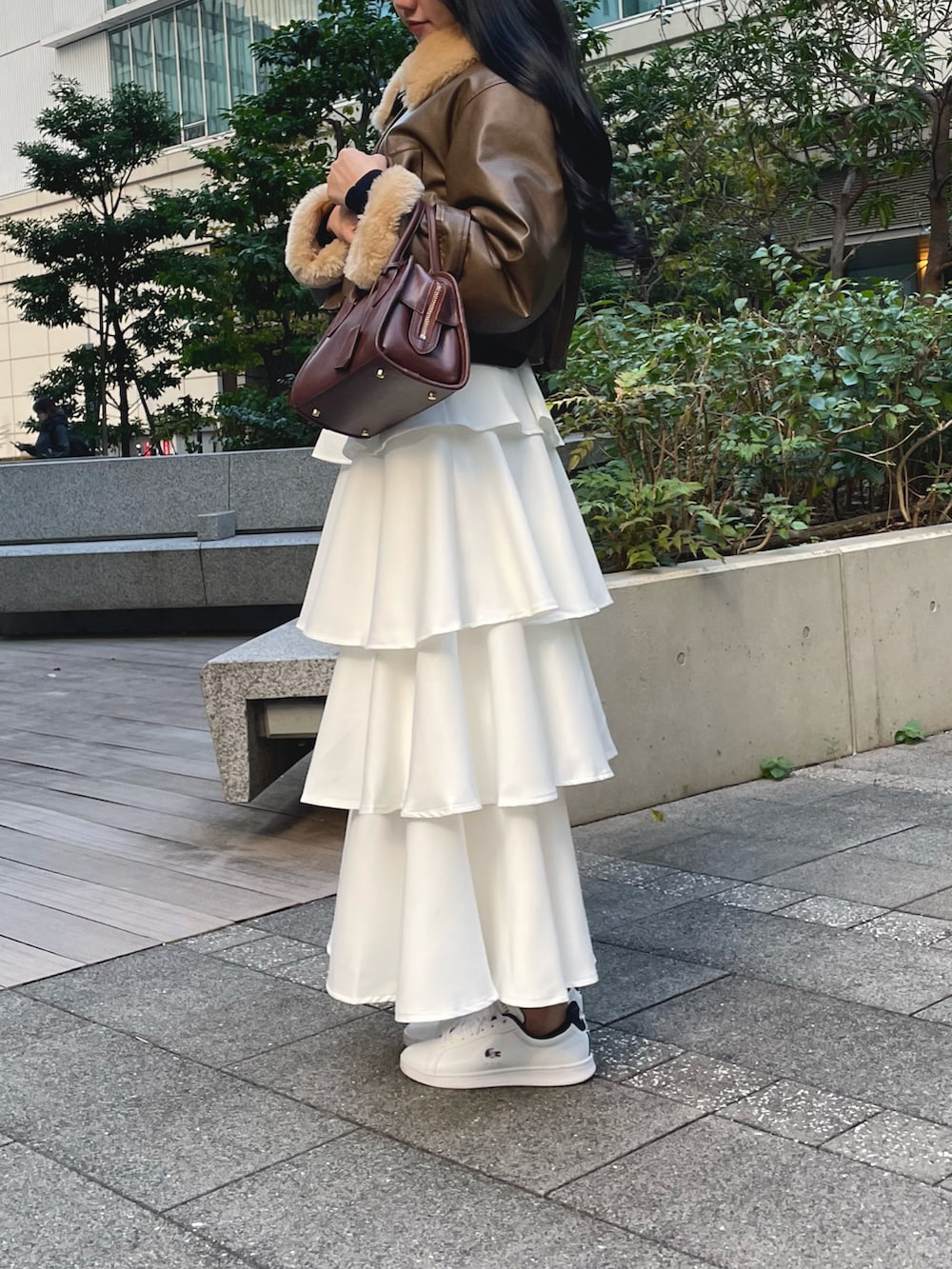 ブラウン系のその他アウター、ホワイト系のスカート、ホワイト系のスニーカーを着用したレディースの秋コーディネートの2枚目の写真