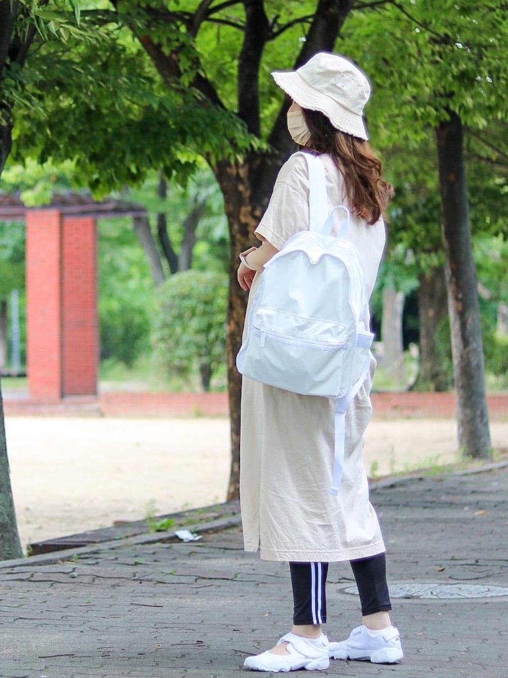 ホワイト系のバックパック/リュック、ホワイト系のサンダル、ベージュ系のハットを着用したレディースの夏コーディネートの2枚目の写真