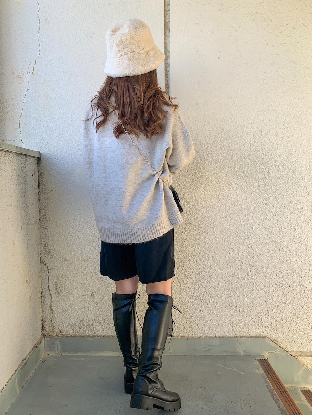 ブラック系のブーツ、ホワイト系のニット/セーター、ホワイト系のハットを着用したレディースの秋コーディネートの2枚目の写真