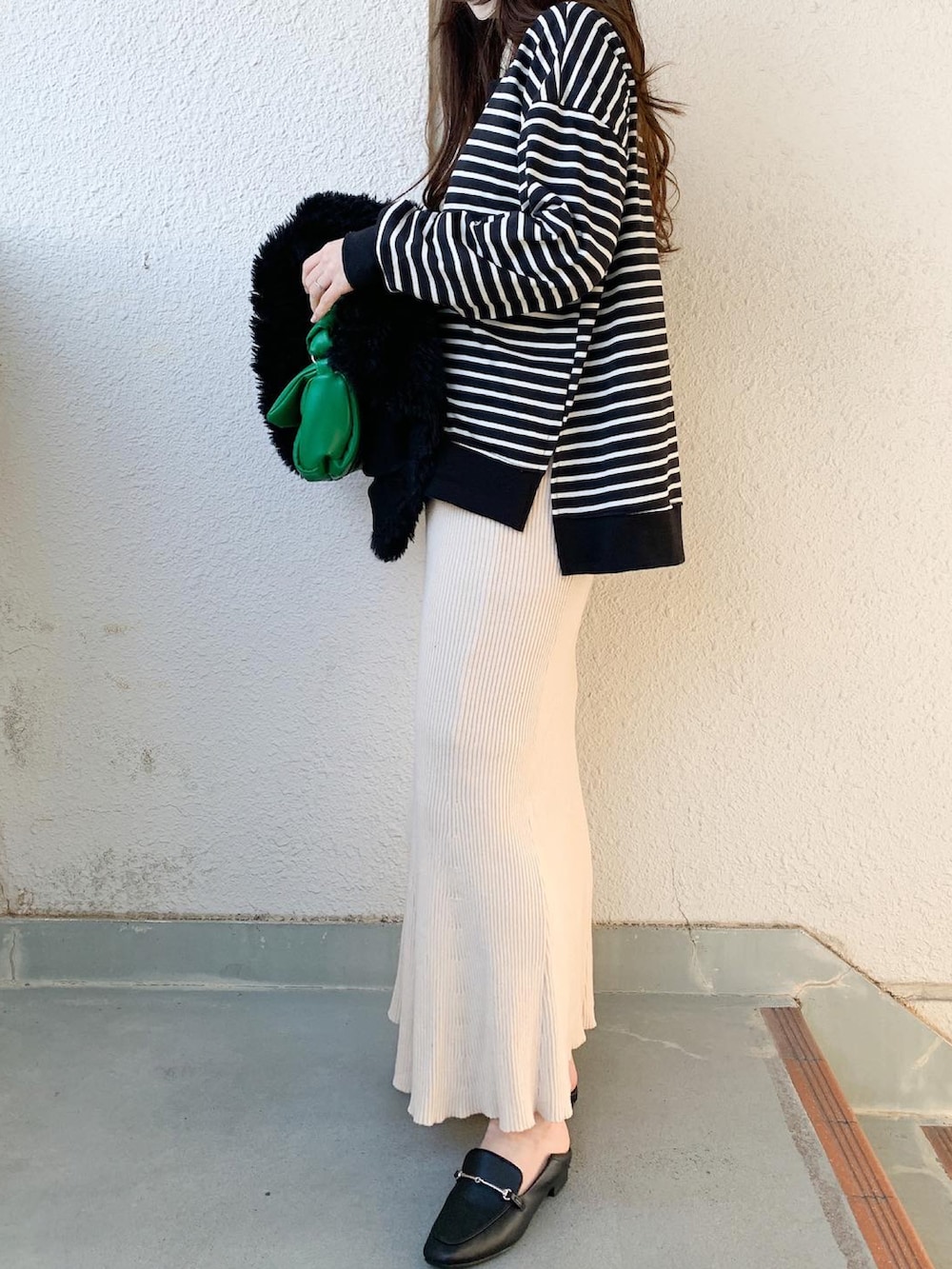 グリーン系のバッグ、ベージュ系のスカート、ブラック系のシューズを着用したレディースの冬コーディネートの2枚目の写真