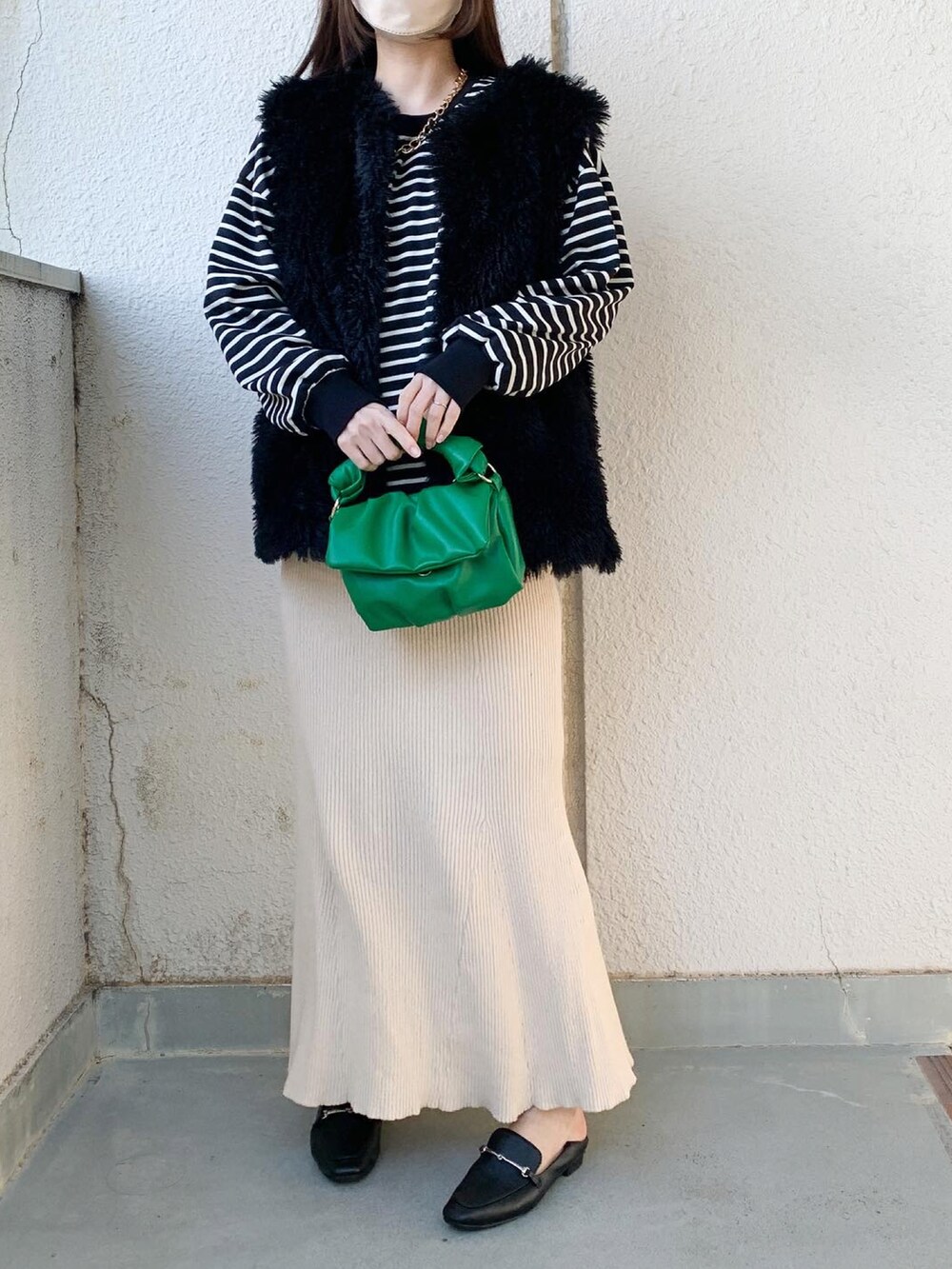 グリーン系のバッグ、ベージュ系のスカート、ブラック系のシューズを着用したレディースの冬コーディネートの3枚目の写真